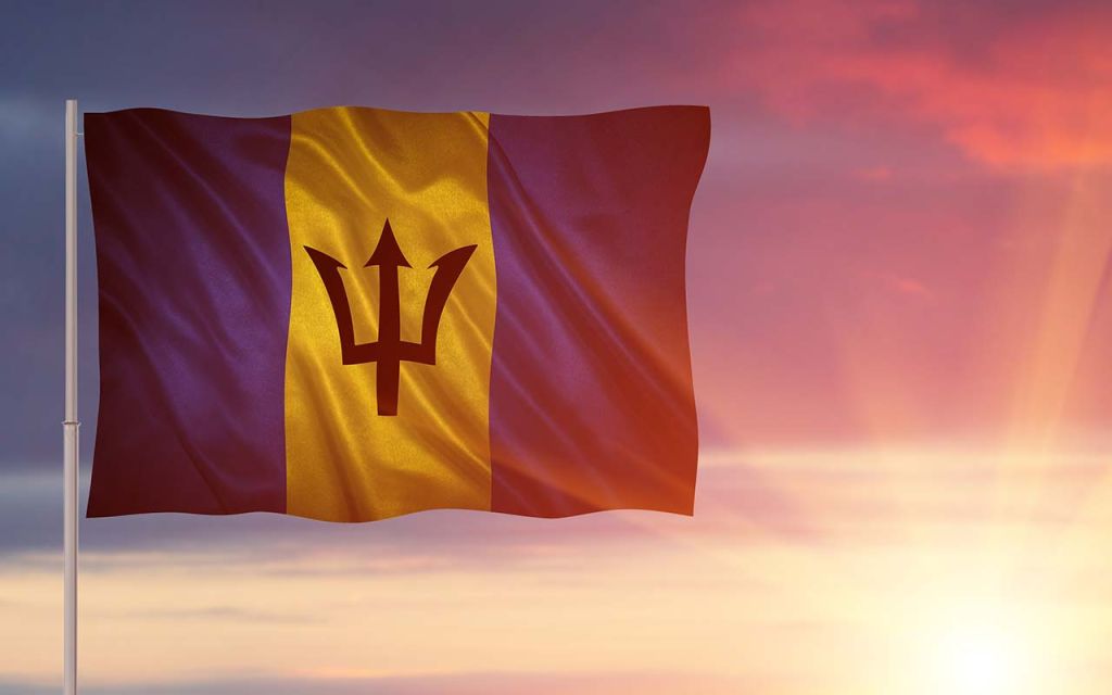 The Flag of Barbados in front of a setting sun.